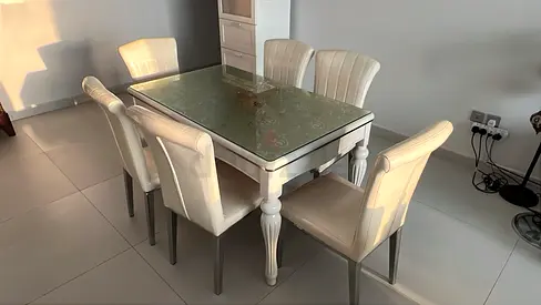 White wooden dining table with glass top and 6 cream chairs