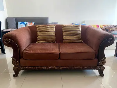 Two-seater brown upholstered sofa with carved wooden frame