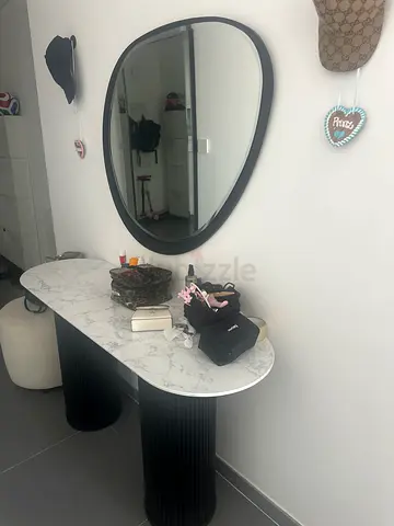 Marble-top console table with black fluted pedestal base and matching oval mirror