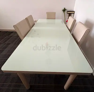White glass-top dining table with 6 beige chairs