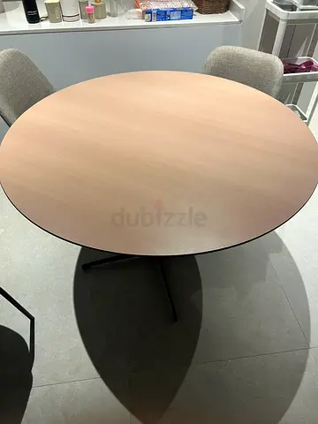 Round light-wood dining table with metal base