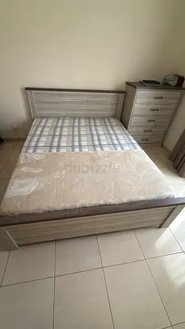 Queen-size wooden bed frame with mattress and pillows