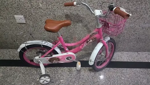 Pink children's bike with training wheels and front basket - good condition