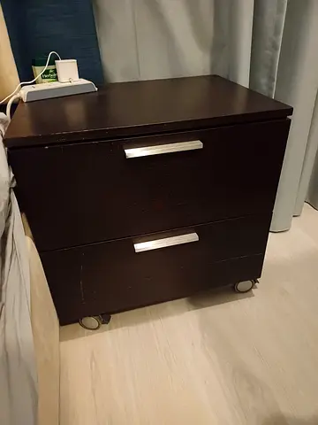 Dark wood 2-drawer bedside cabinet on wheels - good condition.2pic Available