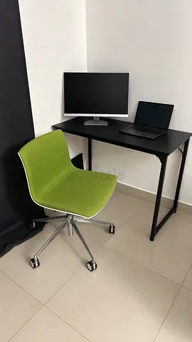 Compact black corner desk and green swivel chair