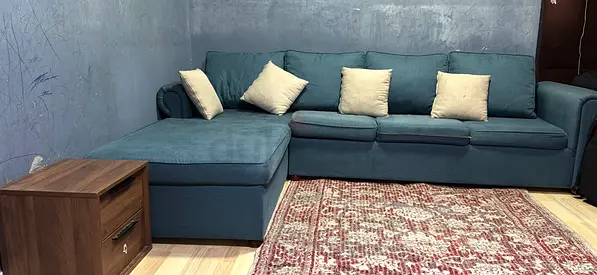 L-shaped teal fabric sofa with chaise and cushions - good condition
