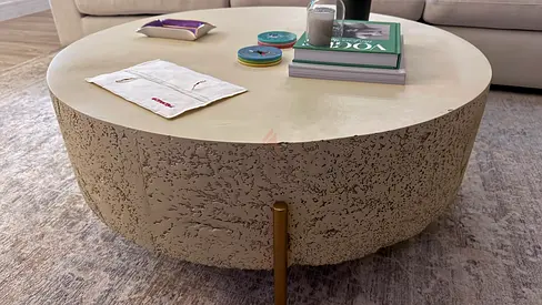 Round textured concrete-style coffee table with brass legs