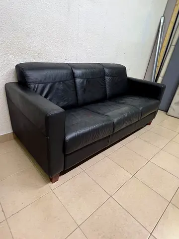 A modern three-seater black leather sofa featuring square armrests and wooden legs, resembling the I