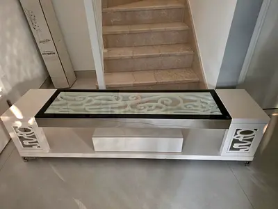 White modern TV unit with glass top and decorative side panels