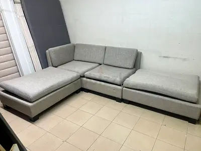 A light gray fabric modular sofa, featuring matching ottomans and low, dark block-style legs.