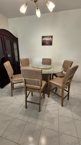 Round glass-top dining table set with central rotating section and 6 chairs.