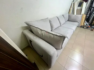 A modern sectional sofa upholstered in light gray fabric, featuring wide armrests with striking roun