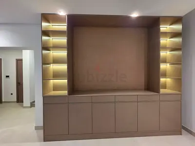Built-in entertainment unit with cabinets and lit display shelves - beige/brown