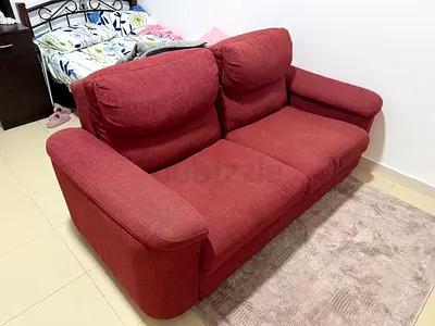 Red 2-seater fabric sofa in good used condition