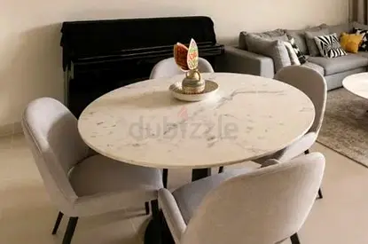 Round marble-top dining table with 4 grey upholstered chairs