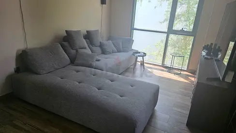Large L-shaped grey green fabric sofa with chaise