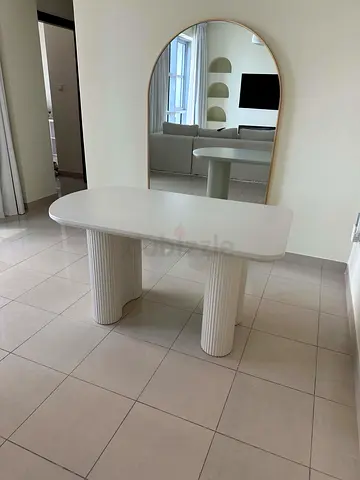 Modern white dining table with rounded top and fluted pedestal legs