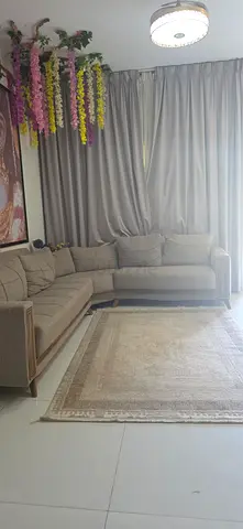 Light beige L-shaped fabric sofa with cushions and center table