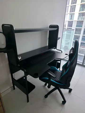 Compact black study desk with shelving and gaming chair