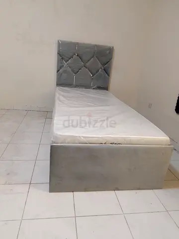 Single upholstered bed with padded headboard -