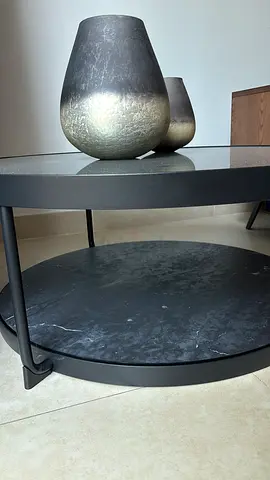 Round black metal coffee table with lower shelf