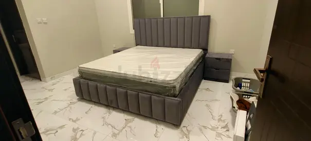 Grey upholstered queen bed frame with mattress with side drawers.