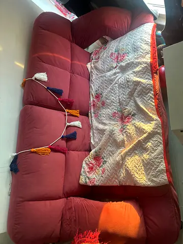 Red three-seater fabric sofa in good used condition