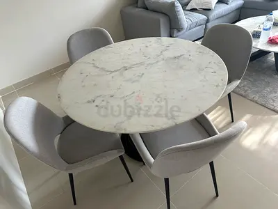 Round marble-top dining table with 4 grey upholstered chairs