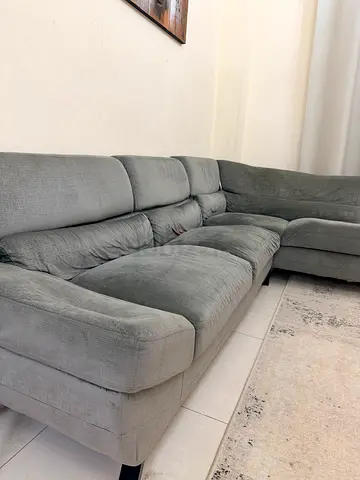Light grey L-shaped fabric sofa, used.