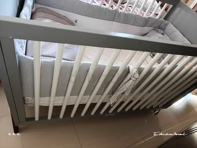Grey wooden baby crib with mattress and bumper — good condition