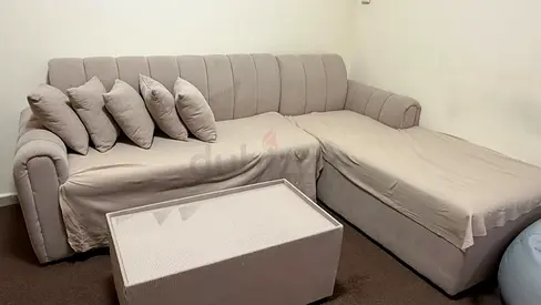 Light beige L-shaped fabric sofa with chaise and cushions