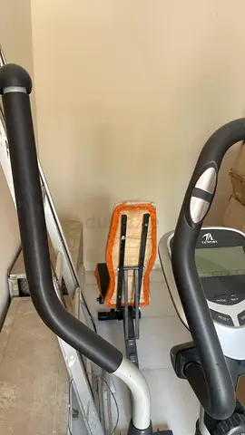 A nice looking cross trainer with a bench