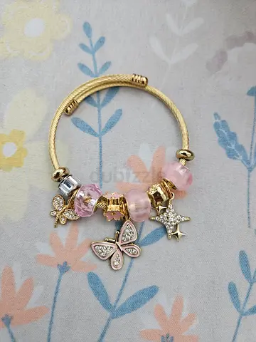 Gold-tone charm bracelet with pink glass beads and butterfly/star charms