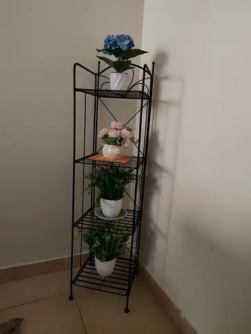 Tall black metal corner shelving unit for plants & decor