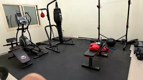 Home gym setup with bench, elliptical, punching bag and free weights