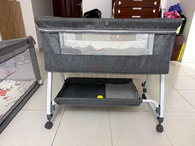 Gray bedside bassinet with storage shelf and wheels - good condition