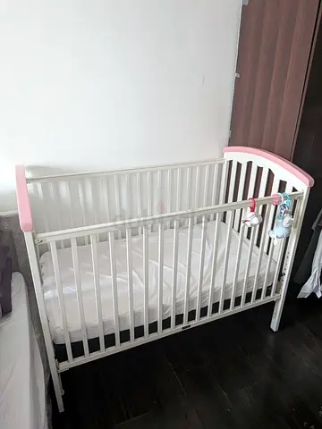 White wooden baby crib with pink accents - good condition