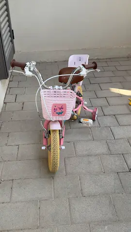 Pink kids bicycle with training wheels and front basket - good condition