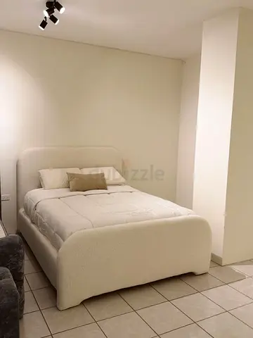 White upholstered double bed with curved headboard and footboard