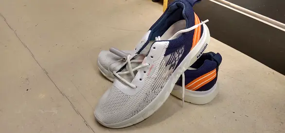 Light grey athletic running shoes with navy and orange accents, used