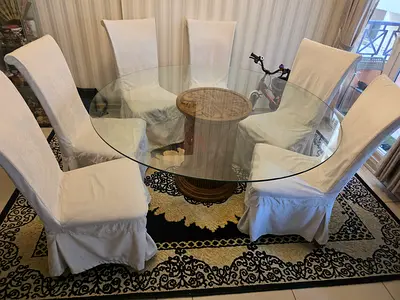 Round glass dining table with wooden pedestal base and 6 slipcovered chairs