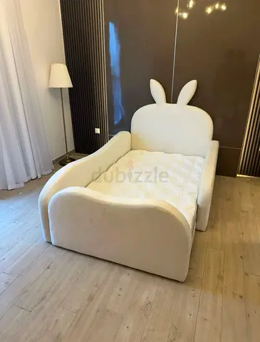 Cream upholstered single bed with playful rabbit-ear headboard