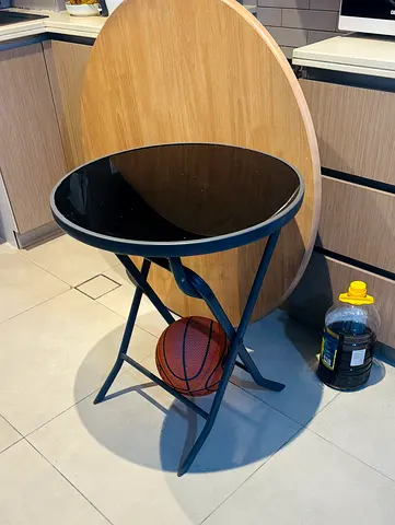 Small round folding side table with black glass top