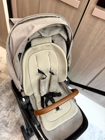 Light grey Nuna  triv next stroller with padded infant insert and leatherette bumper bar