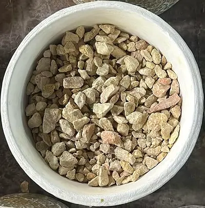 White decorative pot filled with natural beige pebbles - ready for garden or indoor use