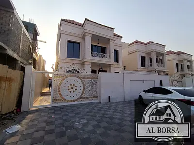 For sale, a villa in Al Helio 2, Ajman, consisting of 4 master bedrooms, a majlis, a hall, and a maid’s room, including registration fees.