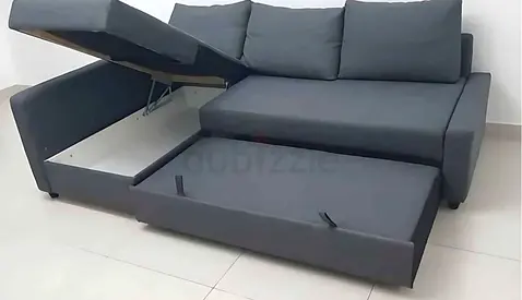 Dark grey L-shaped sofa bed with storage and pull-out bed - good condition