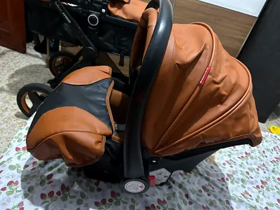 Brown leather-look baby stroller in good condition with baby cot