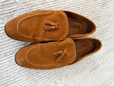 Three pairs of men’s dress shoes — tan brogues, black patent Oxfords, and tan suede tassel loafers