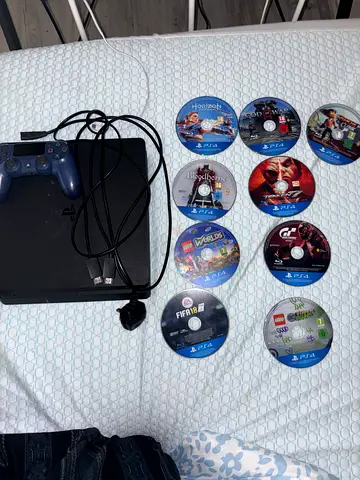 PlayStation 4 Slim with multiple PS4 game discs (FIFA18, $%& of War, Horizon, Tekken 7, more)